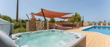 Un jacuzzi y una piscina con sillas de descanso y un muro de piedra.