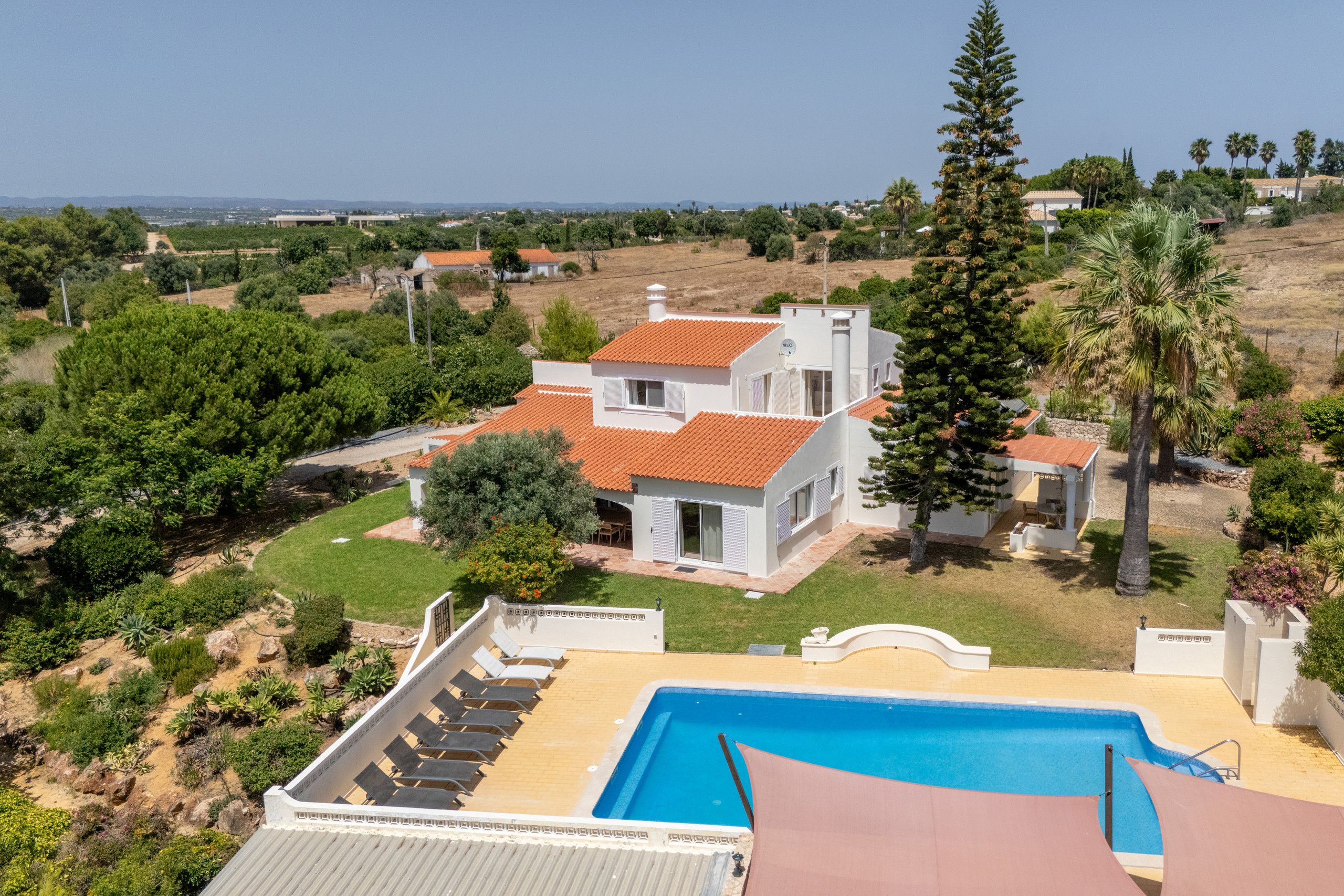 Propiedad residencial con piscina, jardín y vista del paisaje circundante.