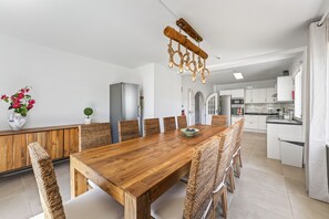 A modern kitchen with white cabinets, a wooden dining table, and a unique rope light chandelier. - Villa Ursa | 6 bedrooms | Jacuzzi | Benagil (Carvoeiro)