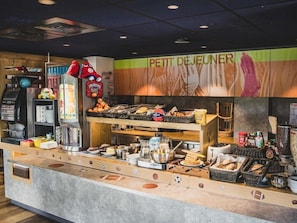 Ein Frühstücksbuffet mit verschiedenen Speisen und einer Kaffeemaschine.