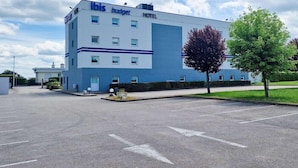 A modern hotel building with a flat roof, multiple windows, and a parking lot in front. - Ibis Budget Dijon Saint Apollinaire (Saint-Apollinaire)