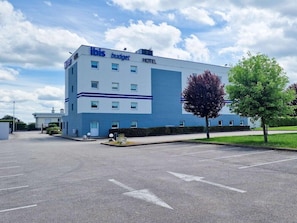 A modern hotel building with a flat roof, multiple windows, and a parking lot in front. - Ibis Budget Dijon Saint Apollinaire (Saint-Apollinaire)