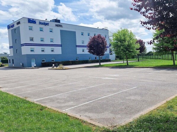 Ein modernes Hotel mit flachem Dach, zahlreichen Fenstern und einem Parkplatz.