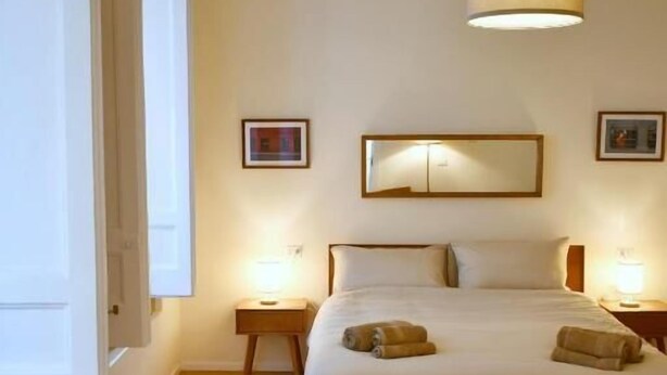 Une chambre à coucher avec un lit, des lampes de chevet, un luminaire suspendu et un tapis.