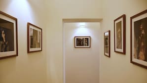 Un couloir avec des tableaux encadrés accrochés aux murs, un plancher en bois et un luminaire au plafond.