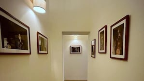 Un couloir avec des tableaux encadrés accrochés aux murs, un plancher en bois et un luminaire au plafond.