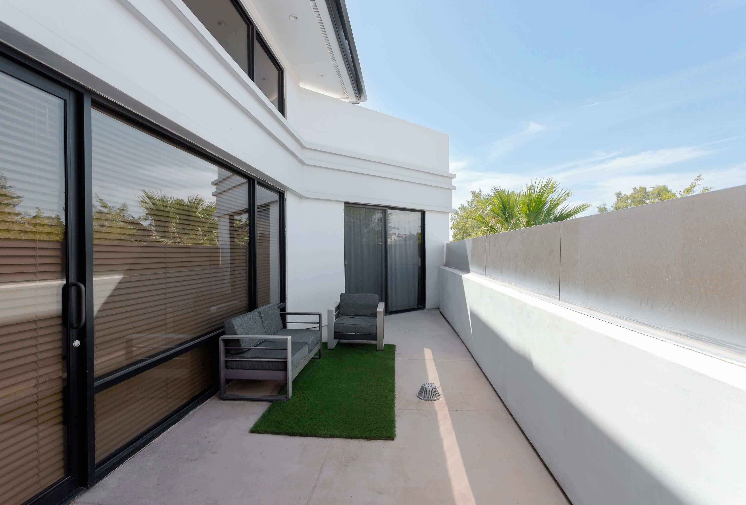 Un balcon extérieur moderne, aménagé avec un canapé, des fauteuils et une petite table.