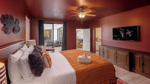 Habitación de hotel con cama, televisor, ventilador de techo y vista al exterior.