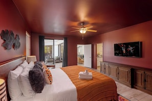 Ein Hotelzimmer mit Bett, Fernseher, Deckenventilator und Blick ins Freie.