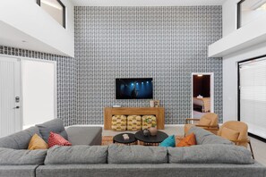 Un soggiorno moderno con un divano grigio, un tavolino da caffè e una TV a parete.