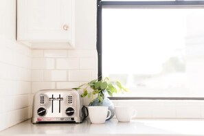 Eine Küche mit einem Toaster, zwei weißen Tassen und einem Blumentopf.