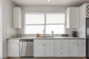Eine moderne Küche mit weißen Schränken, einem eingebauten Geschirrspüler, einem Toaster und einer Kaffeemaschine.