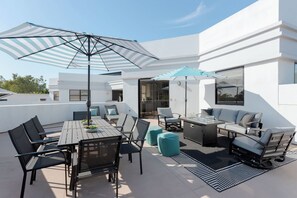 An outdoor patio with a dining table, chairs, a sofa, and two umbrellas. - Zeta - Private Balcony - In Old Town Scottsdale (Scottsdale)