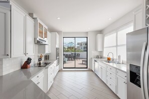 A modern kitchen with white cabinetry, a stainless steel refrigerator, and a view to an outdoor patio area. - Zeta - Private Balcony - In Old Town Scottsdale (Scottsdale)