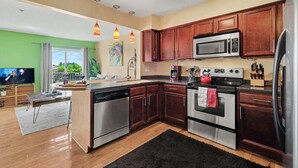 A modern kitchen with stainless steel appliances, wooden cabinets, and pendant lighting.