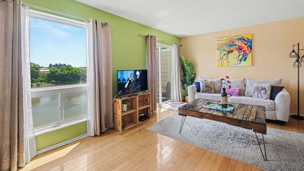 A living room with a television, a white sofa, a coffee table, and a painting on the wall.