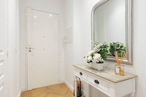 A hallway with a white door, a mirror, a small plant, and a vase with a candle. - Promenade Flat for 3 Guests | 30+ Night Stay (Nice)