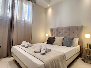 Ein ordentlich bezogenes Bett mit Handtüchern, einem gepolsterten Kopfteil und Nachttischlampen in einem modernen Hotelzimmer.