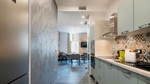 A modern kitchen with a central island, a dining area with a table and chairs, and a TV mounted on the wall. - Large 3-Room Garibaldi – 4 People | Stay 30+ Days (Nice)