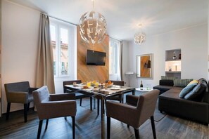 Ein modernes Wohnzimmer mit Essbereich, einer Couch und einem an der Wand befestigten Fernseher.