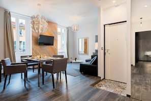 Ein modernes Wohnzimmer mit Essbereich, einer Couch, einem an der Wand montierten Fernseher und einem großen Fenster.