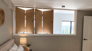 Une chambre à coucher avec un grand lit, une table de chevet avec une lampe, une fenêtre donnant sur un beau paysage et une armoire.
