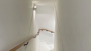 Un escalier étroit aux murs blancs et à la rampe en bois.