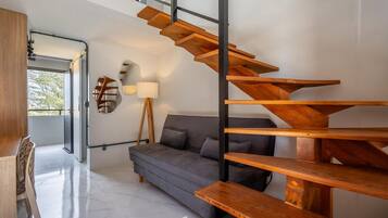 Un interior moderno con una escalera de madera, un sofá gris y una lámpara.