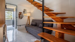 A modern interior with a wooden staircase, a grey sofa, and a lamp. - Loft 50 m From Camacho Beach Plo0005 (Jaguaruna)
