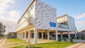 A building with a geometric facade, a sign indicating 'Peak Loftetil,' and a covered parking area. - Loft 50 m From Camacho Beach Plo0005 (Jaguaruna)