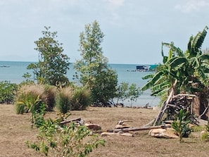 A beach with trees, a small structure, and a body of water in the background. - Sea View Villa Property (Phu Quoc)