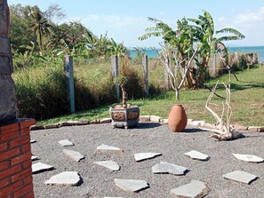 A garden with a decorative pot, a large urn, and stepping stones. - Sea View Villa Property (Phu Quoc)
