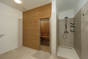 A bathroom with a wooden panel wall, a shower with a handheld showerhead, and a white door. - Villa Astrid (Istria - Krničari) (Krničari)
