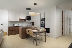 A modern kitchen with a central island, built-in appliances, and a dining area with chairs and a table. - Villa Astrid (Istria - Krničari) (Krničari)