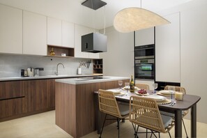 A modern kitchen with a central island, built-in appliances, and a dining area with wicker chairs. - Villa Astrid (Istria - Krničari) (Krničari)