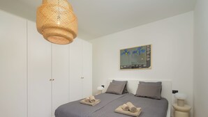 Une chambre à coucher comprenant un lit, une armoire, un luminaire suspendu, une œuvre d’art accrochée au mur et des lampes de chevet.