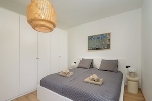 A bedroom with a bed, a wardrobe, a hanging light fixture, a wall-mounted artwork, and bedside lamps. - Villa Astrid (Istria - Krničari) (Krničari)