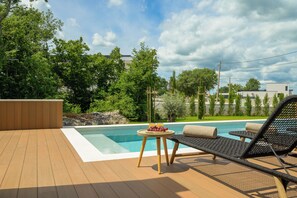 A wooden deck with a pool, lounge chairs, and a table with fruit. - Villa Astrid (Istria - Krničari) (Krničari)