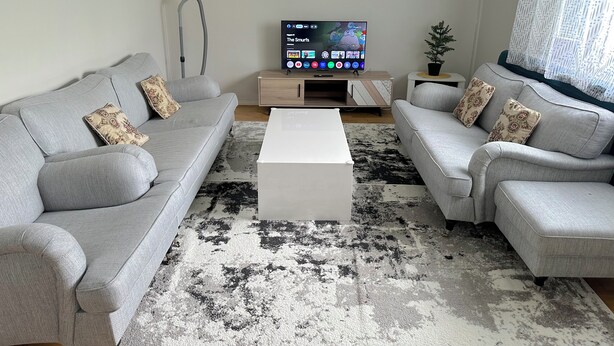 A living room with two grey sofas, a white coffee table, and a TV on a stand. - Helsinki Airport & City Center Gateway (Helsinki)