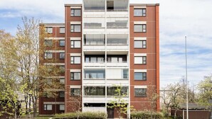 A multi-story residential building with a central atrium, balconies, and a brick facade. - Helsinki Airport & City Center Gateway (Helsinki)