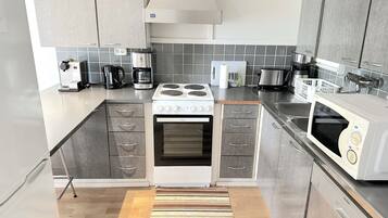 Una cocina moderna con gabinetes grises, estufa, microondas y cafetera.
