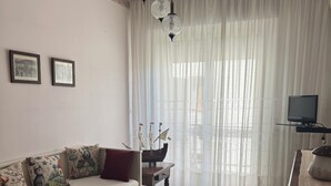 En stue med sofa, et lille bord, et fjernsyn og en dekorativ skibsmodel.