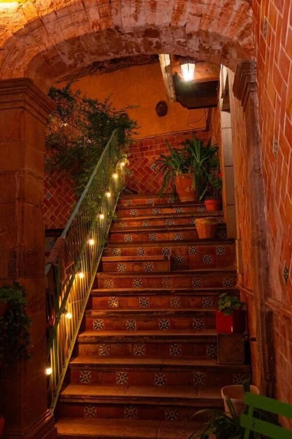 A staircase with patterned steps, a brick wall, and potted plants.