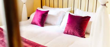 A bed with white linens and two red pillows, a wooden headboard, and a red quilted bedspread.