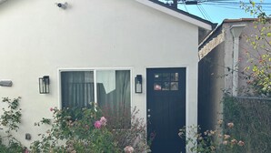 Una casa con puerta negra, ventana con cortina y un pequeño porche.