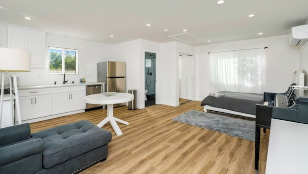 Un apartamento moderno con kitchenette, comedor, sofá y cama.