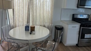Una cocina moderna con una mesa redonda, sillas, microondas, estufa y un cubo de basura.