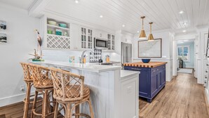 A modern kitchen with white cabinetry, a central island, wicker bar stools, and pendant lighting. - Gorgeous Oceanfront Villa, Wild Dunes Resort. Phenomenal Views of Ocean and Community Pool, Unit 56 (Isle Of Palms)