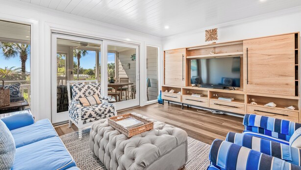 A spacious living room with a large TV, comfortable seating, and a sliding glass door leading to an outdoor area. - Gorgeous Oceanfront Villa, Wild Dunes Resort. Phenomenal Views of Ocean and Community Pool, Unit 56 (Isle Of Palms)