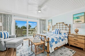 Une chambre avec un grand lit, une chaise, une table de chevet et une vue sur l’extérieur.